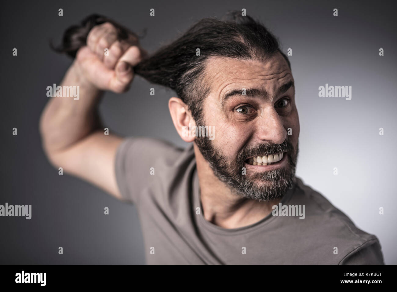 Verärgert man seine Haare mit der Hand studio Portrait halten Stockfoto