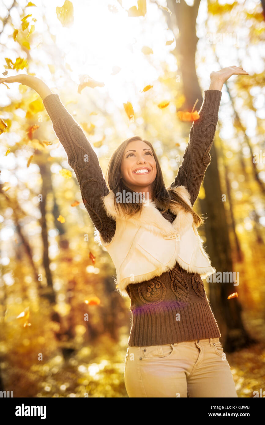 Nette junge Frau, die Spaß im sonnigen Wald im Herbst Farben. Stockfoto