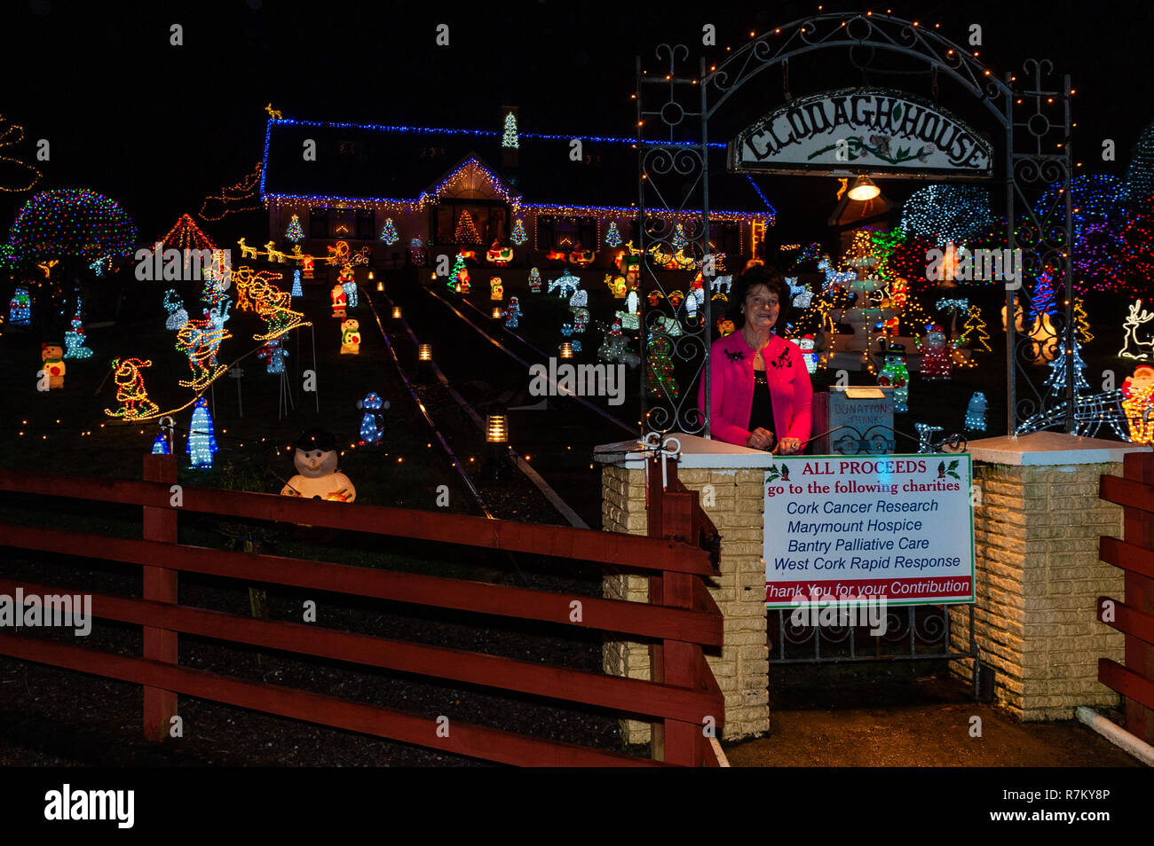 Dunmanway, West Cork, Irland. 10 Dez, 2018. Noreen McSweeney steht stolz am Tor zu Ihrem Haus mit Tausenden von Weihnachtsbeleuchtung hinter ihr. Noreen hat sich auf eine leichte Display für 20 Jahre in Höhe von verschiedenen Nächstenliebe. Credit: Andy Gibson/Alamy Leben Nachrichten. Stockfoto