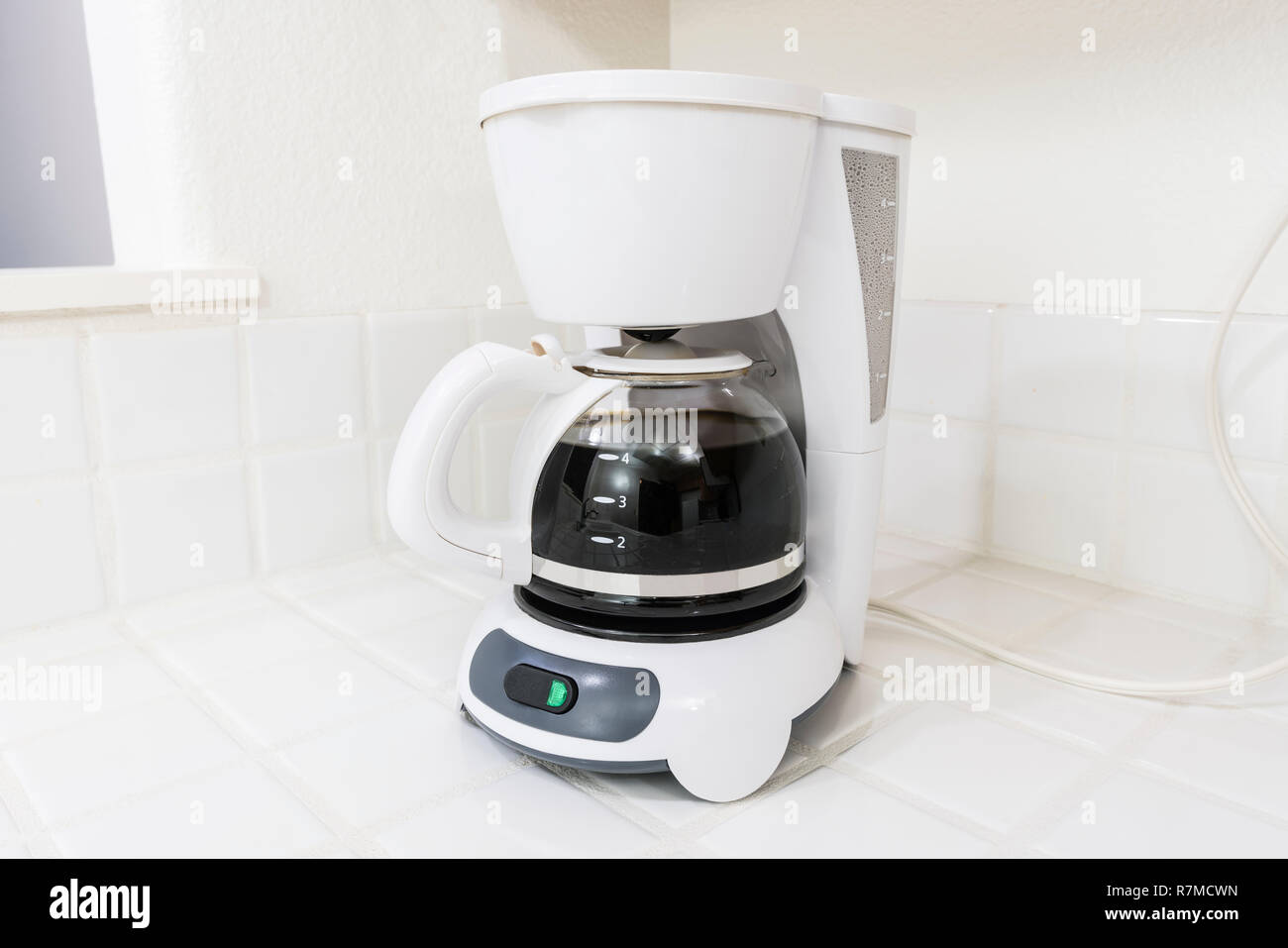 Weiß Kaffeemaschine brühen auf sauberen, weißen Fliesen Arbeitsplatte in der Küche. Stockfoto Weiß Kaffeemaschine brühen auf sauberen, weißen Fliesen Arbeitsplatte in der Küche. Stockfoto