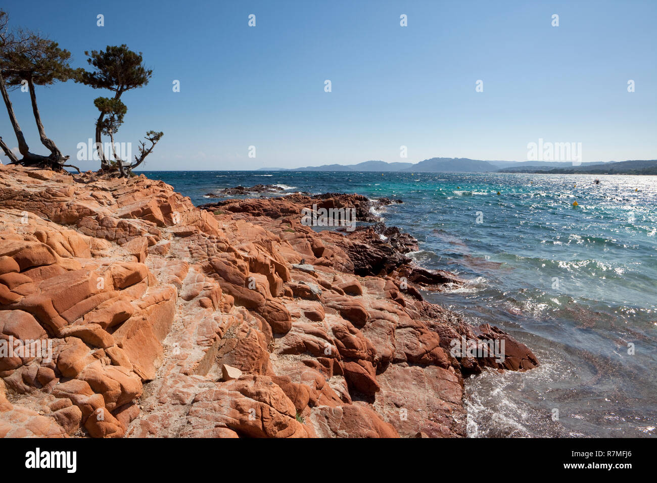 Die typischen roten Felsen von Palombaggia Strand auf der Insel Korsika. Berge von Süden Korsika im Hintergrund. Stockfoto