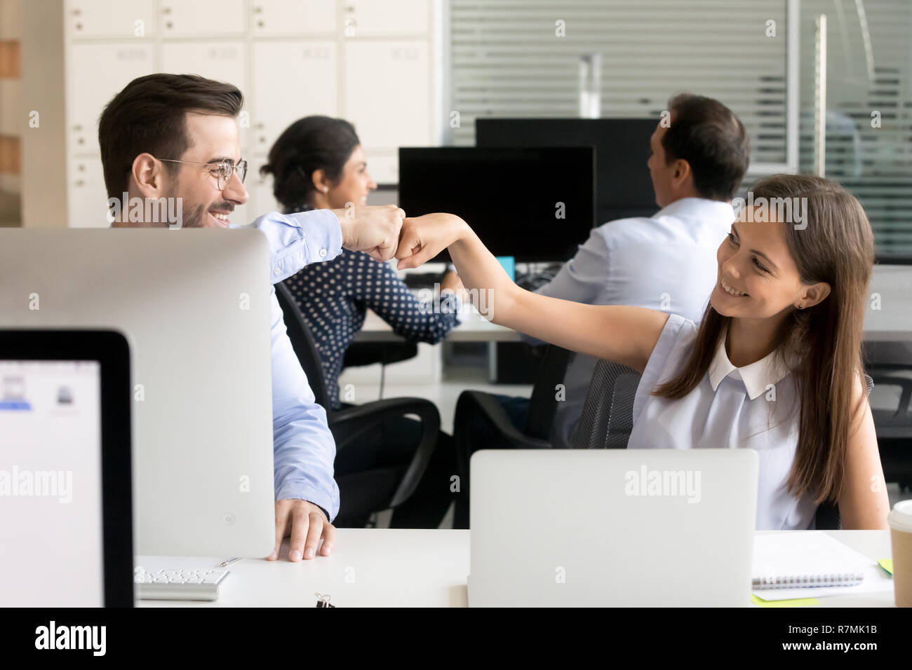 Freundlich lächelnden Kollegen Faust stoßen am Arbeitsplatz Stockfoto