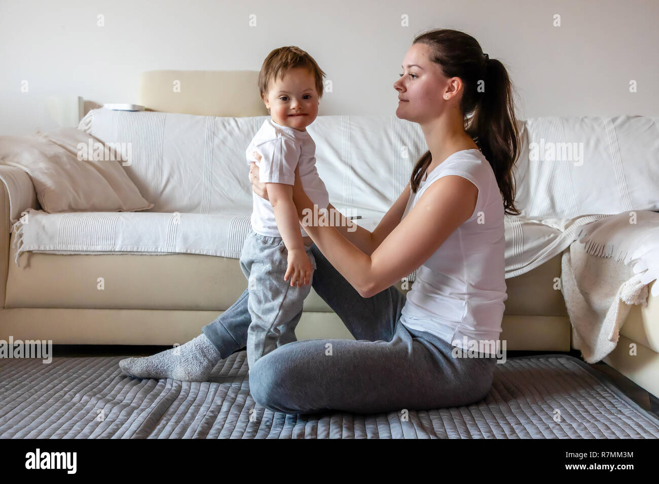 Niedlichen kleinen Jungen mit Down Syndrom spielen mit Mutter in Home Stockfoto