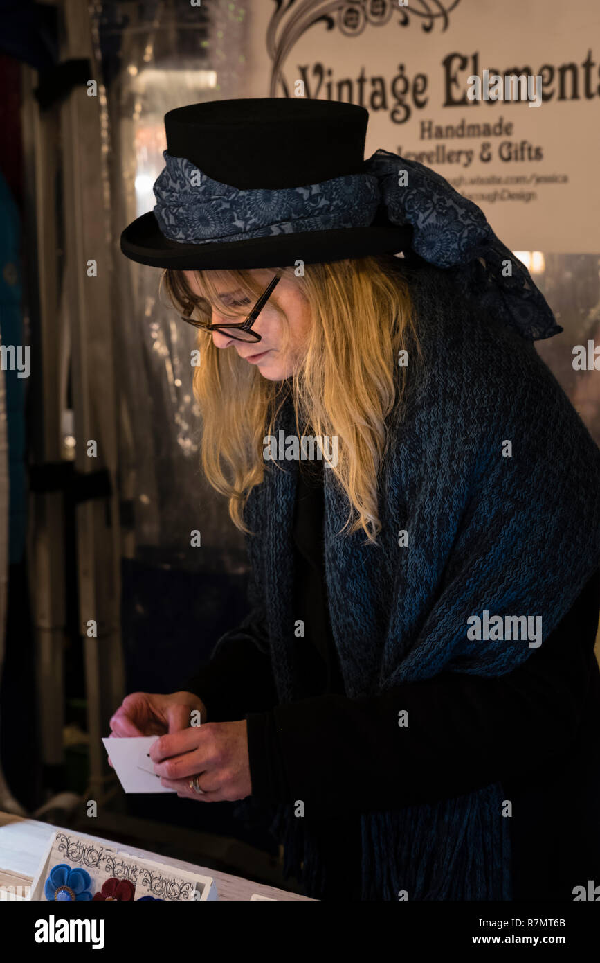 Junge Frau mit langen blonden Haaren in der traditionellen Tracht verkaufen Schmuck an der Viktorianischen Weihnachtsmarkt, Stratford-upon-Avon Stockfoto