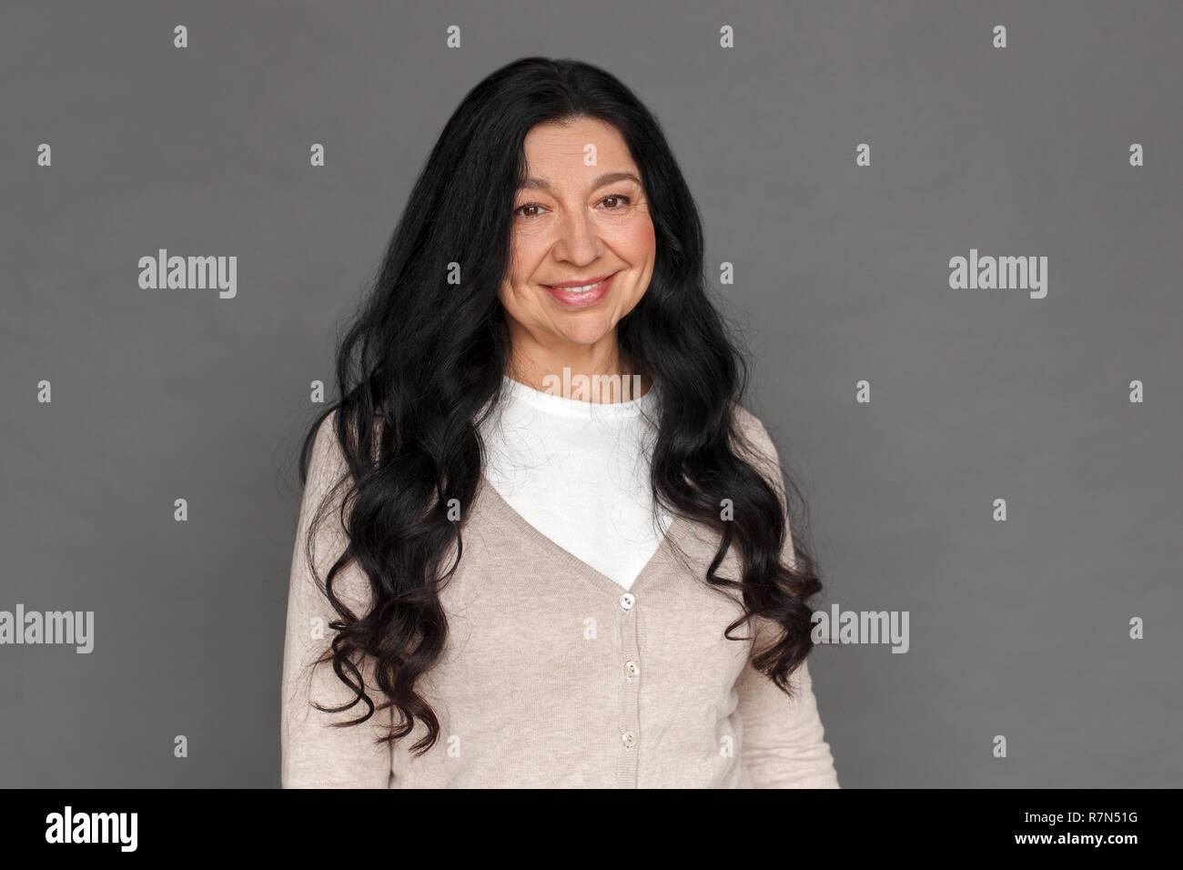 Freestyle. Reife Lady stehen isoliert auf Grau lächelt glücklich Stockfoto