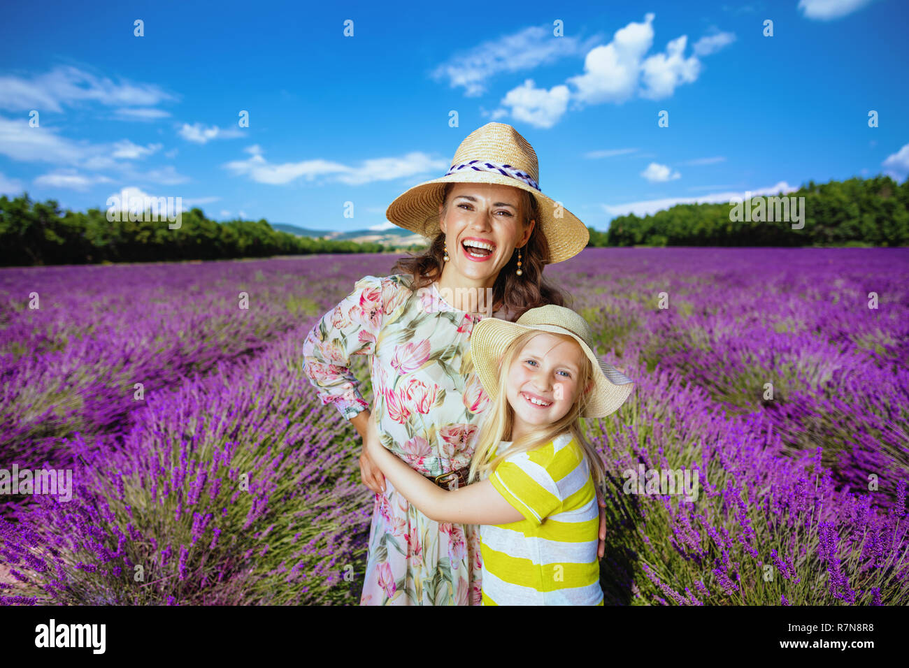 Glückliche junge Mutter und Tochter umarmen gegen Lavendelfeld in der Provence, Frankreich. Sehr nette Familie mit Farbe und Duft von Lavendel Feld. Mutter Stockfoto