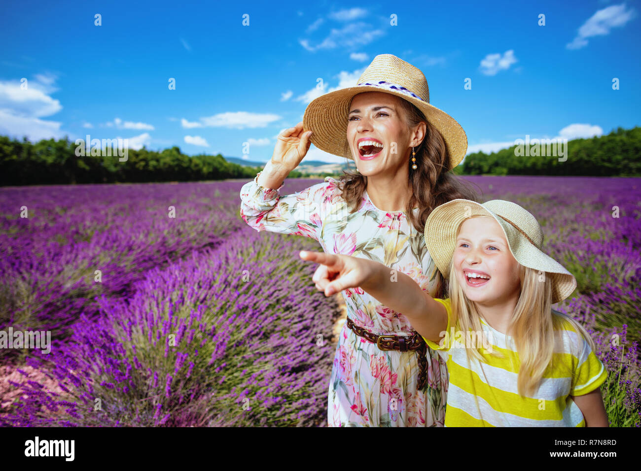 Gerne moderne Mutter und Tochter zeigt auf etwas gegen Lavendelfeld in der Provence, Frankreich. Familie an der Lavendelfelder blicken aufgeregt. Tochter Stockfoto