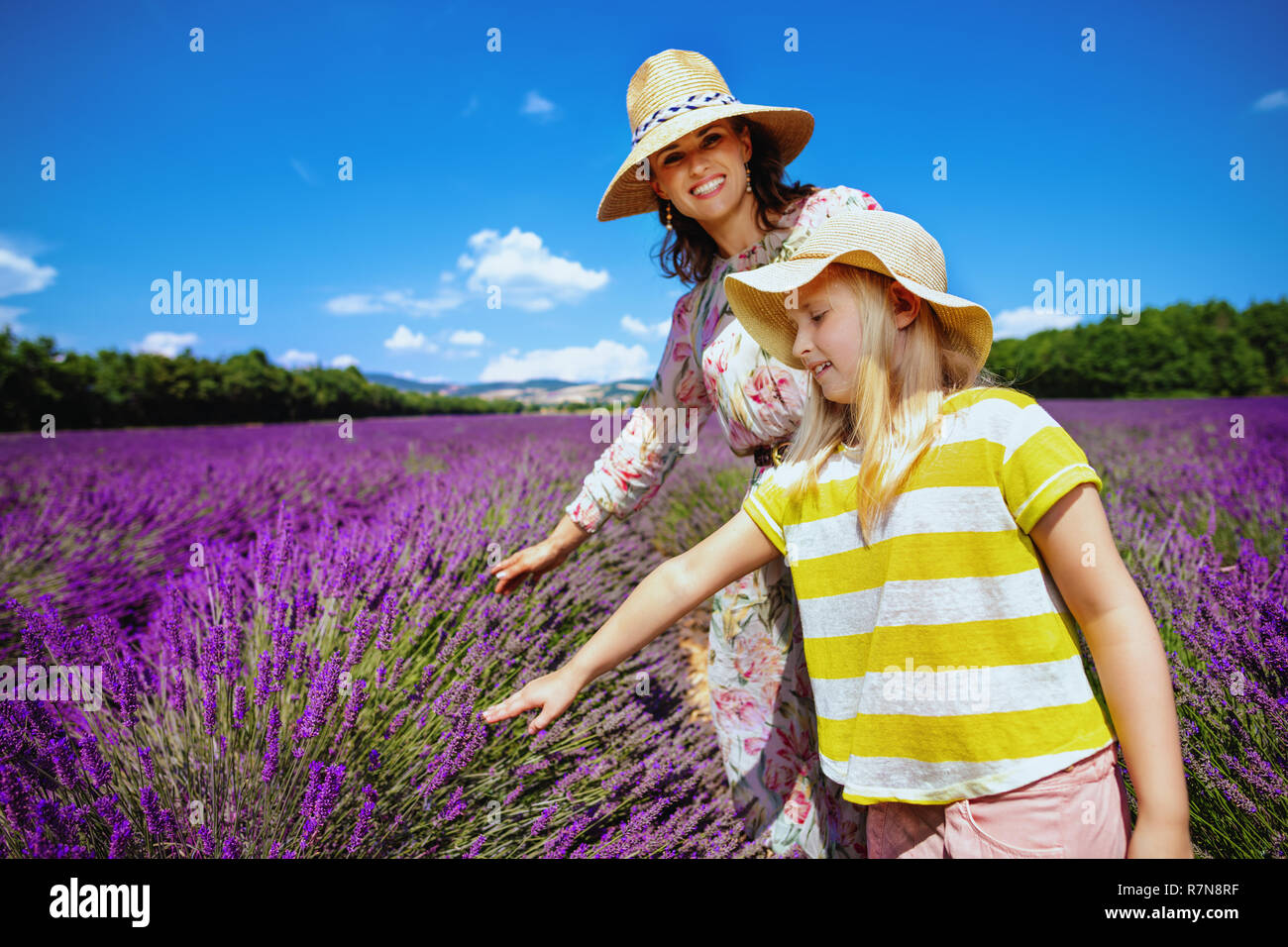 Lächelnde junge Mutter und Kind berühren Lavendel gegen Lavendelfeld in der Provence, Frankreich. Familie Agrotourismus. bis in die Stadt Mutter und Kind lea gewachsen Stockfoto