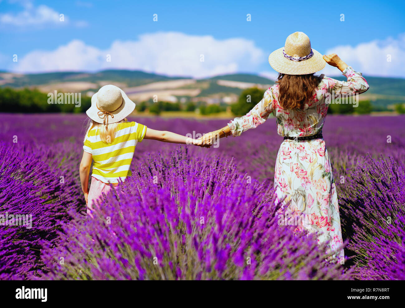 Hinter der jungen Mutter und Tochter gesehen stand halten sich an den Händen gegen Lavendelfeld in der Provence, Frankreich. Nimm meine Hand und lässt die meisten berühmten Lav genießen Stockfoto