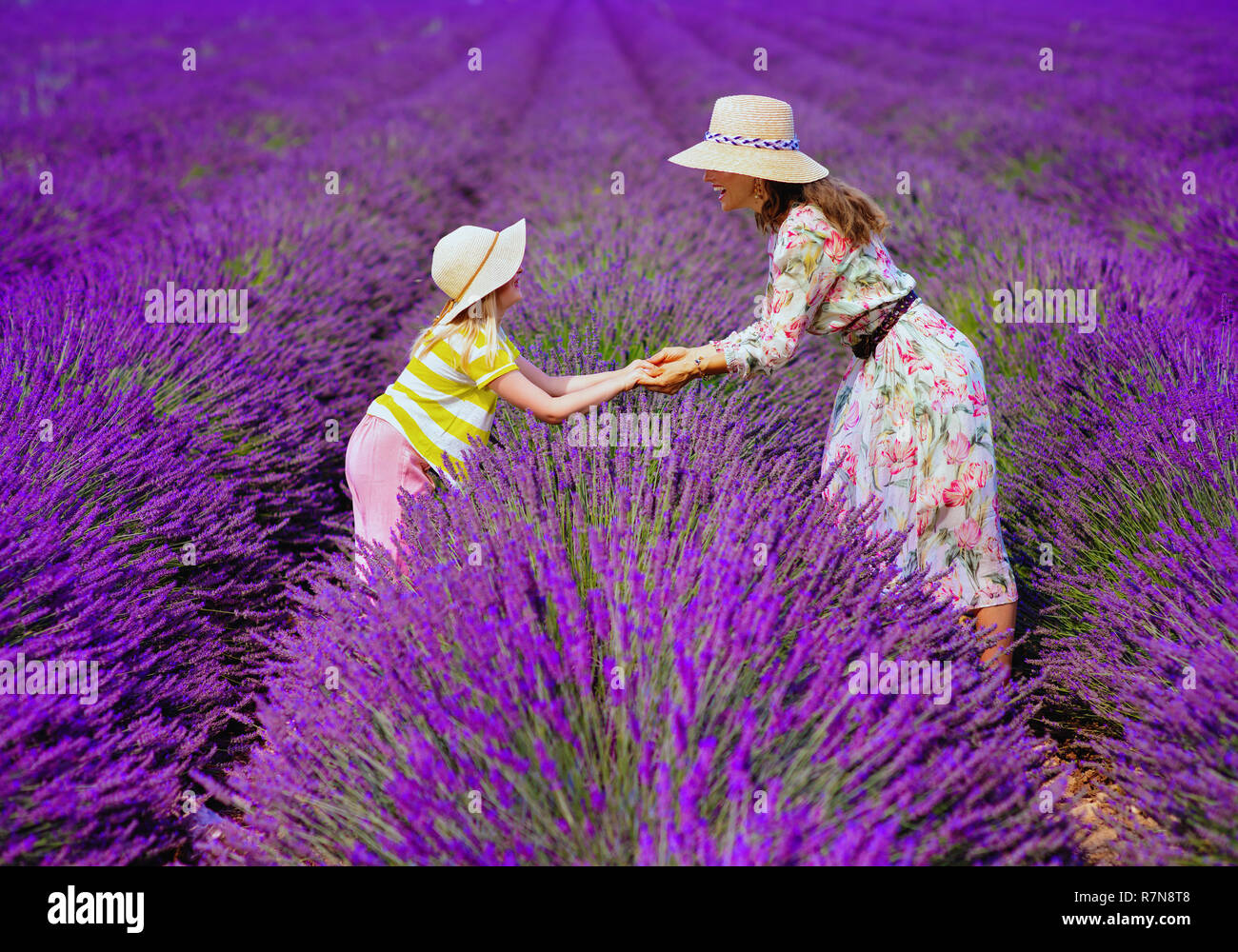 Moderne Mutter und Tochter im lavendelfeld in der Provence, Frankreich stand halten sich an den Händen. entspannt und beruhigt sich abzeichnende Lavendelfeld im Juli oder August ist Stockfoto