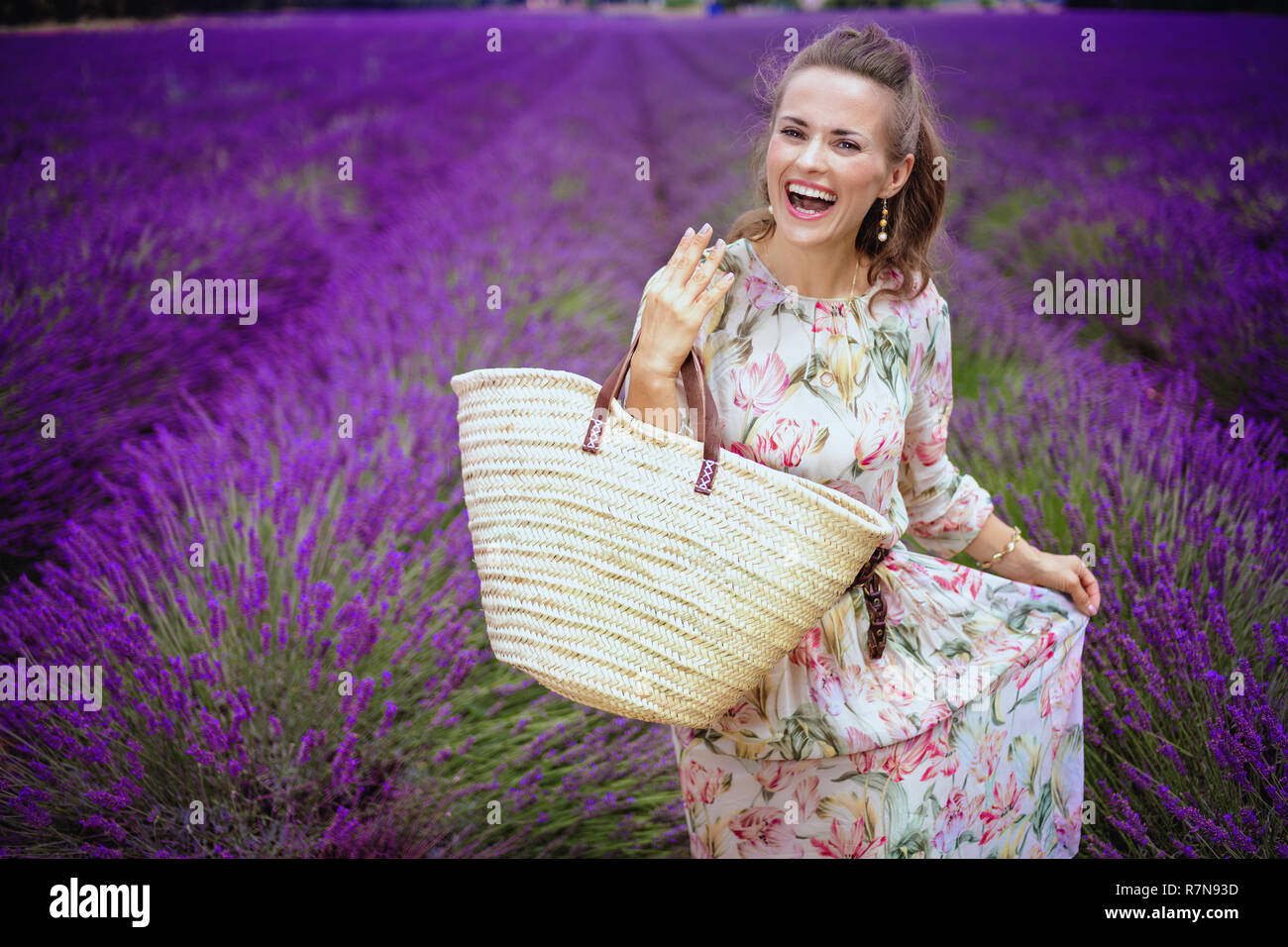 Glückliche junge Frau mit Stroh Beutel in lavendelfeld in der Provence, Frankreich. Lavendelfelder der Provence - ist eine unvergessliche Reise. Verpassen Sie nicht die Ama Stockfoto