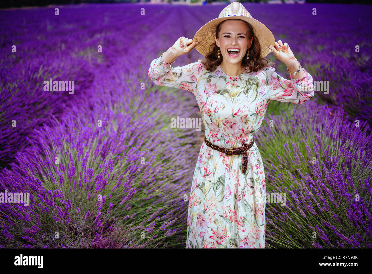 Portrait von Happy trendy Frau im Sommerkleid an lavendelfeld in der Provence, Frankreich im Stroh Hut. Erste, unvergessliche Reise auf dem Plateau de Valensole Platea Stockfoto