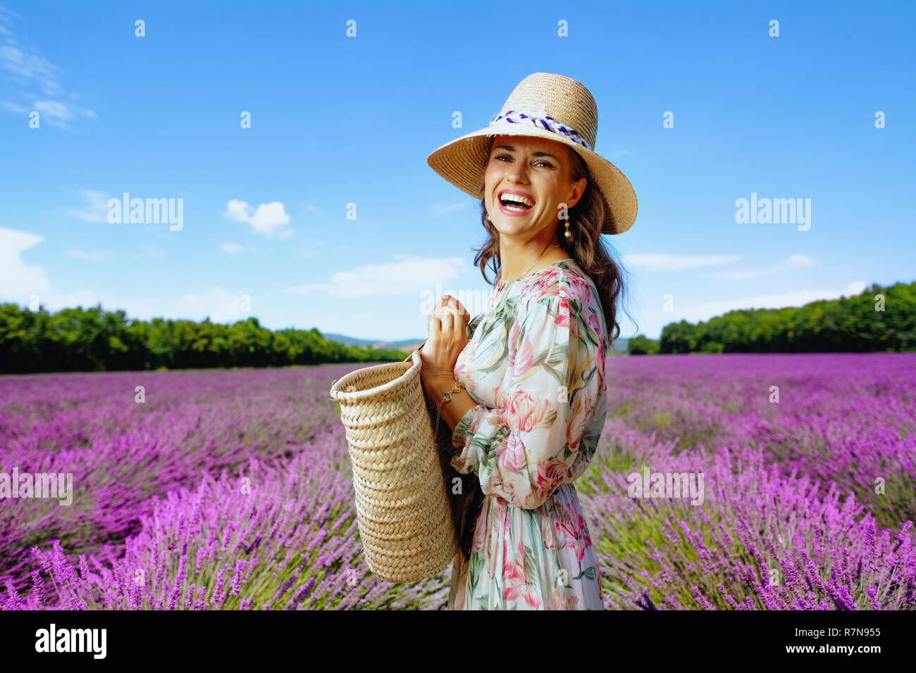 Porträt der glückliche junge Frau im Sommerkleid mit Stroh Beutel gegen Lavendelfeld in der Provence, Frankreich. Perfekte Farbe und Textur für ein Foto zu erhalten Stockfoto