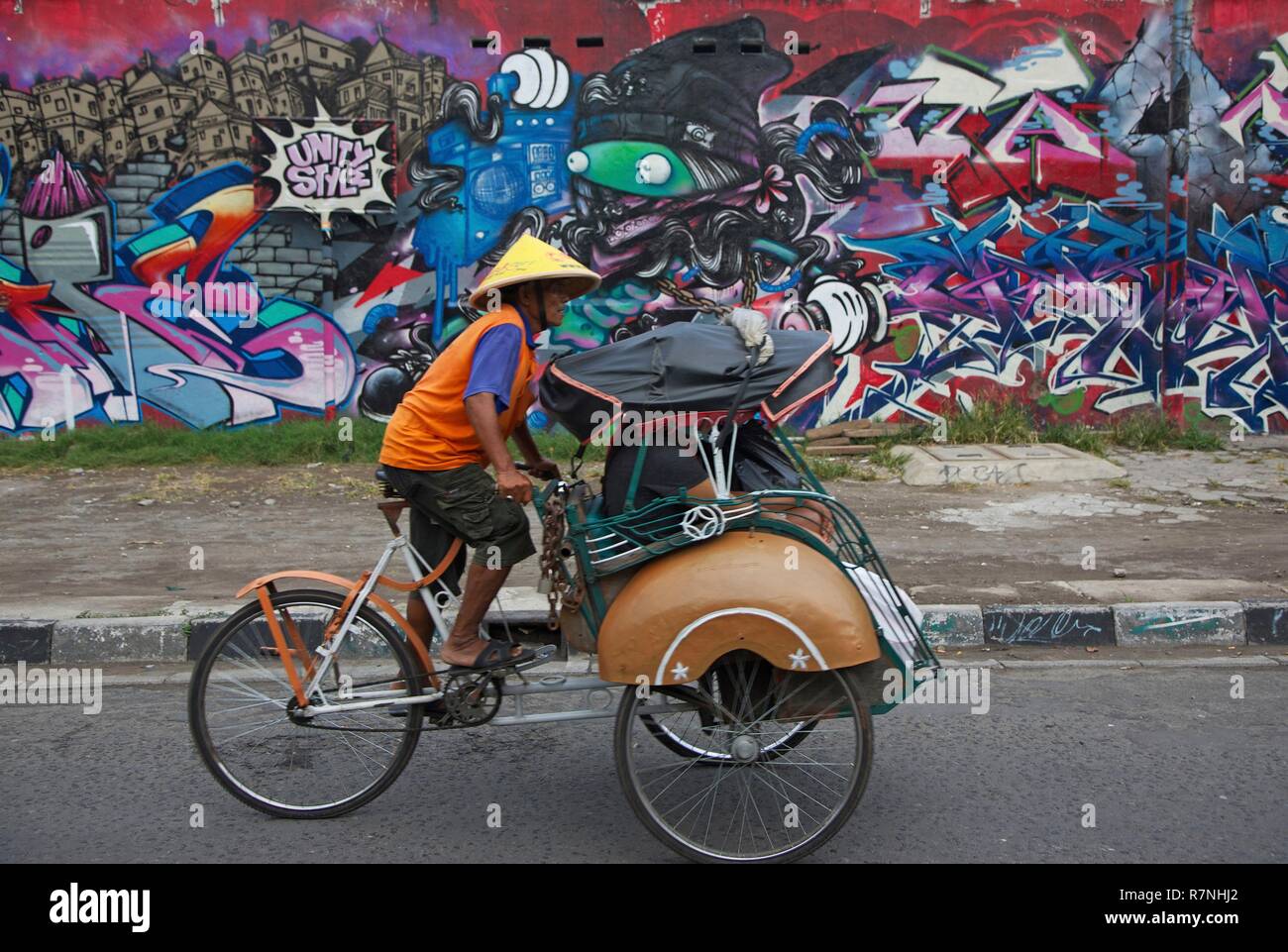 Indonesien, Java, Yogyakarta, Fahrrad rikscha vor einer Wand dekoriert mit Graffitis Stockfoto