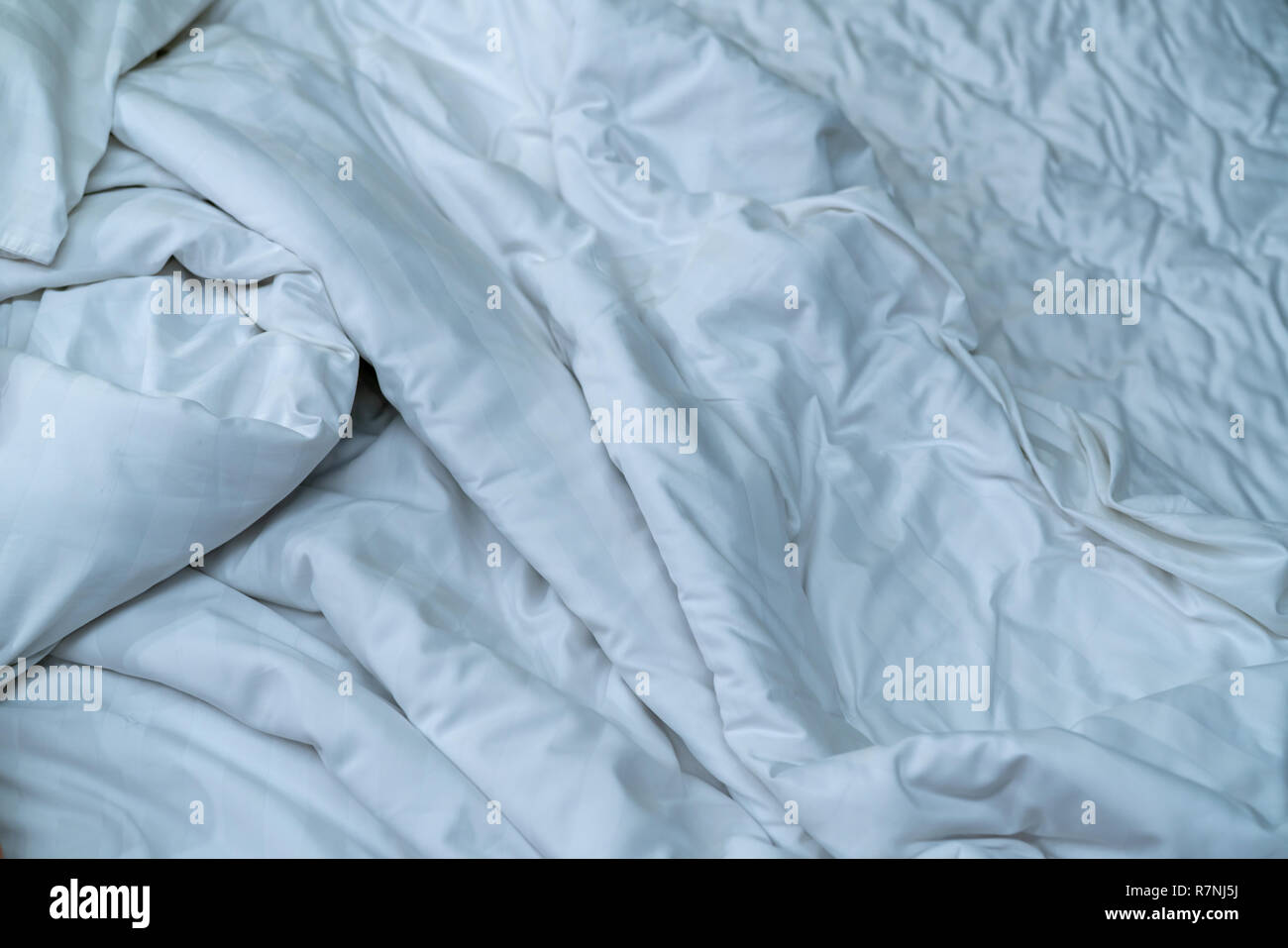 Weiße Bettwäsche Decke im Hotel Schlafzimmer. Nahaufnahme Detail der unordentlichen weiße Decke nach dem Aufwachen am Morgen. Komfortables Bett mit weichen, weißen Bettdecke. Schlafen Stockfoto