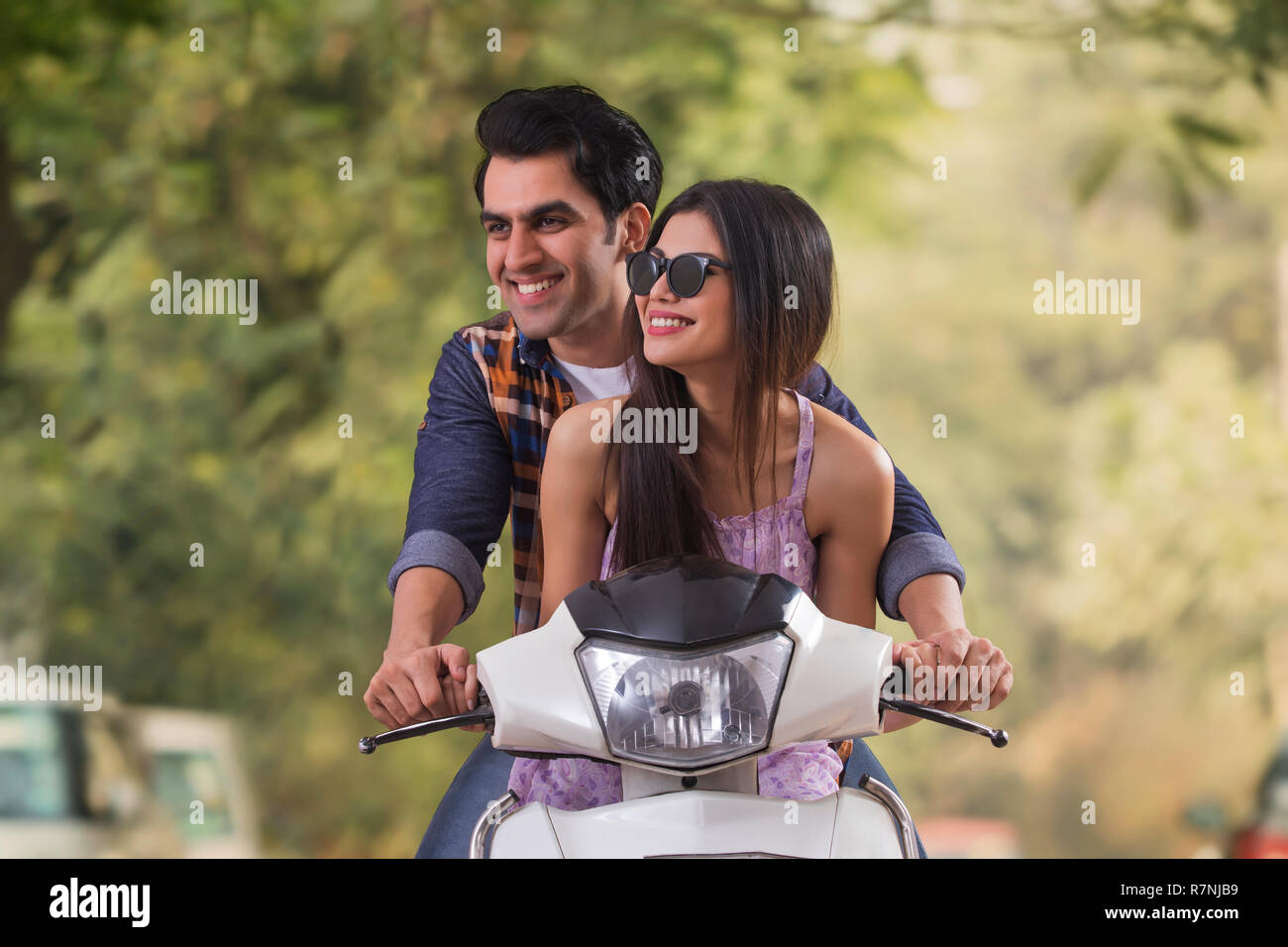 Glückliches junges Paar, das Spaß reiten auf einem Motorroller. Stockfoto