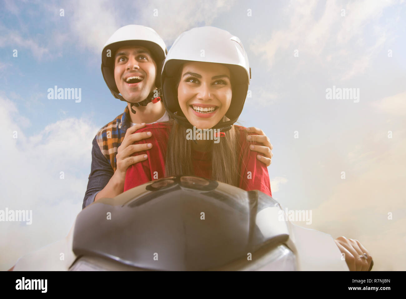 Der junge lächelnde Paar reiten auf einem Motorroller. Stockfoto