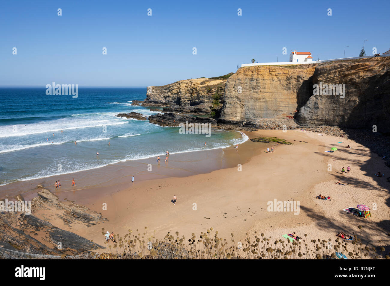 Klippe Kapelle von Igreja de Nossa Senhora do Mar mit Wellen des Atlantiks am Sandstrand in der Morgensonne brechen bei Zambujeira do Mar Stockfoto