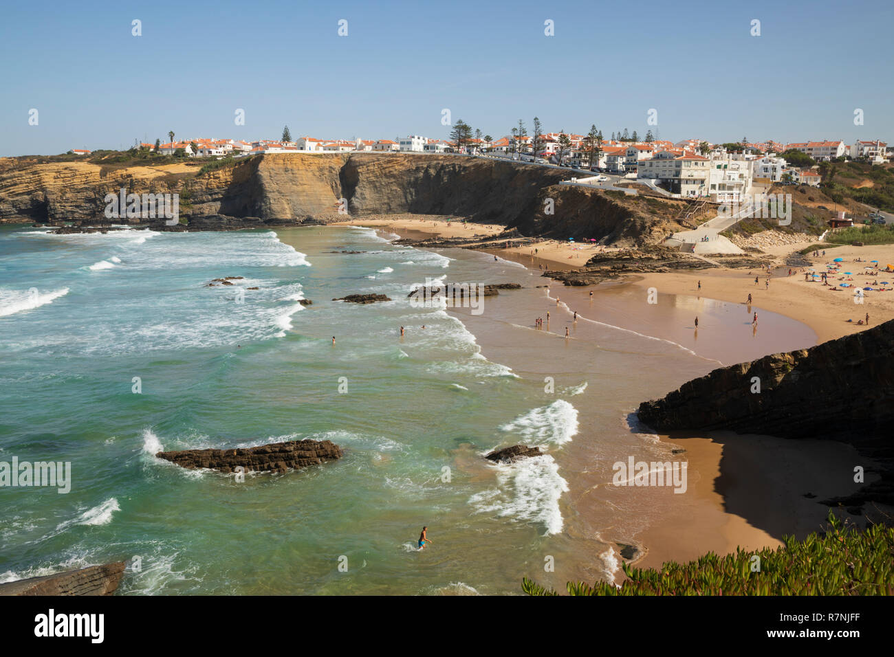 Weiß getünchte Stadt auf Klippen über Strand und brechenden Wellen des Atlantik in der Mittagssonne, Zambujeira do Mar, Alentejo, Portugal, Europa Stockfoto