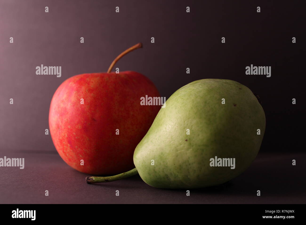 Birne und Apfel ergänzen sich auf grauem Hintergrund Stockfoto