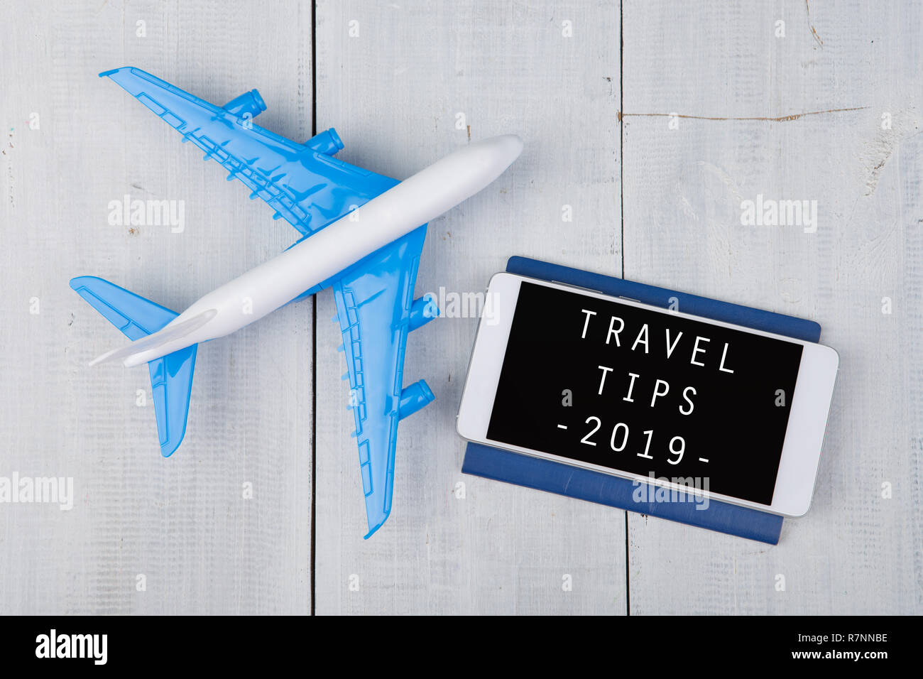 Adventure Time-plane, Reisepass und Smartphone mit Text' Reisetipps 2019' auf weiße Holztisch Stockfoto