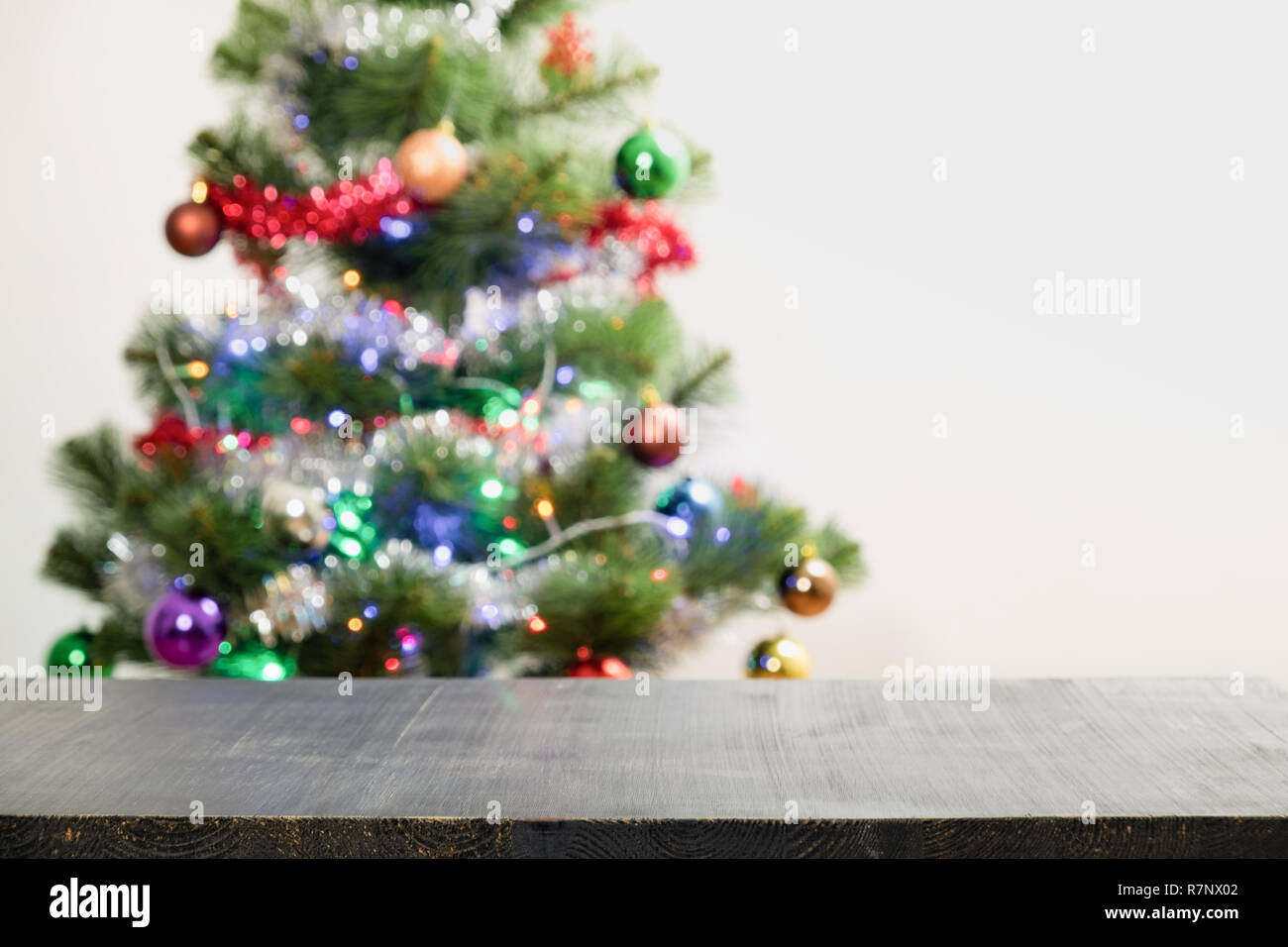 Weihnachten Produkt Hintergrund mit unscharfen Tanne. Vordere Aufnahme des schwarzen Holz Tisch und beleuchtete aus Tanne mit Girlanden Stockfoto