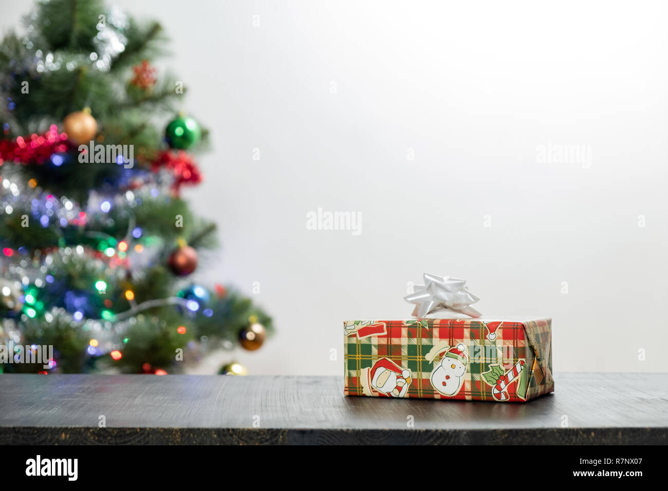 Weihnachtsgeschenk auf Holz Tisch und Kopieren. Vorderansicht des schönen Geschenk und dekorierte Tanne in verschwommenen Hintergrund Stockfoto