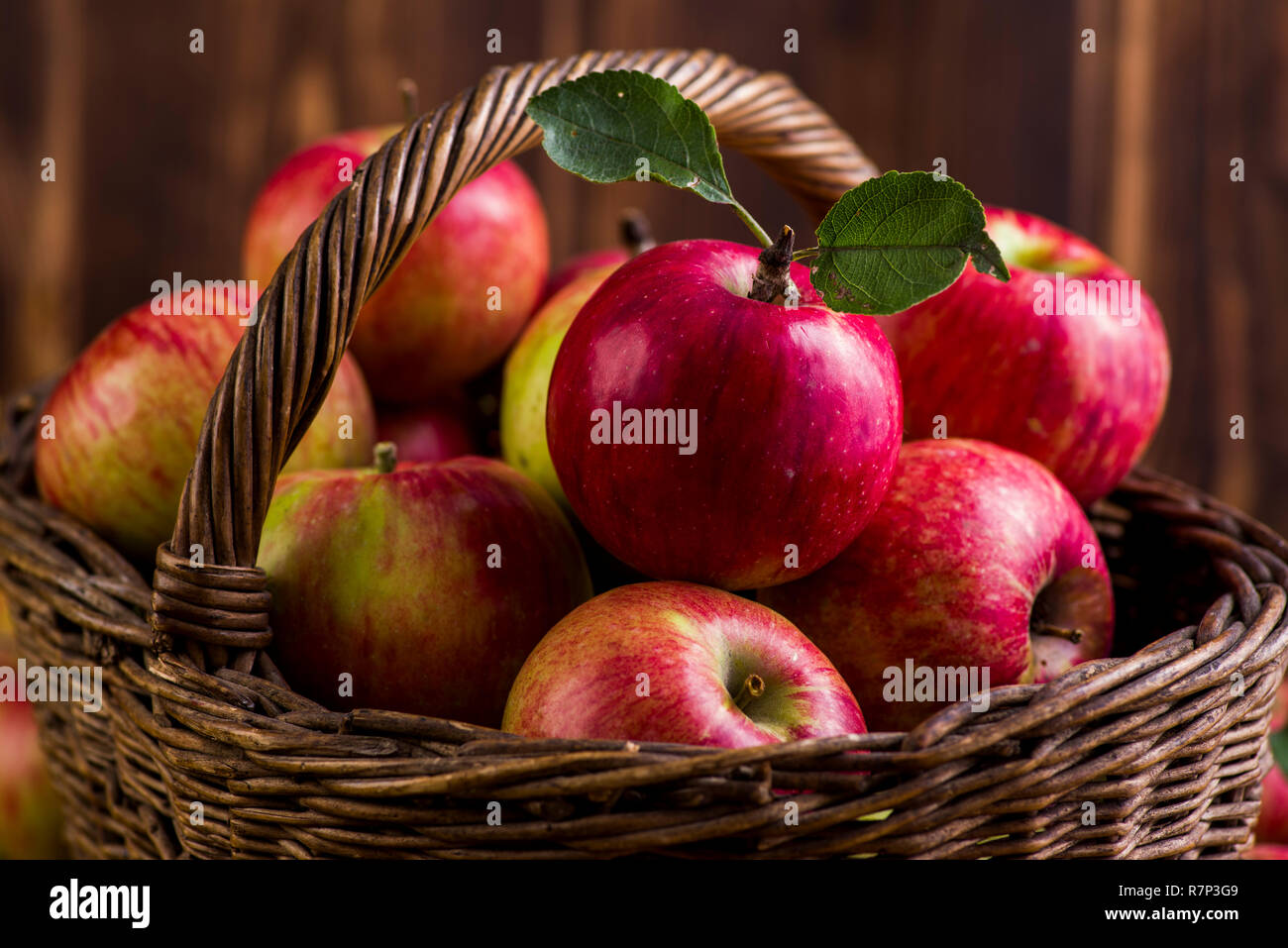 Frische rote Äpfel in einem Korb auf einem Holztisch Stockfoto