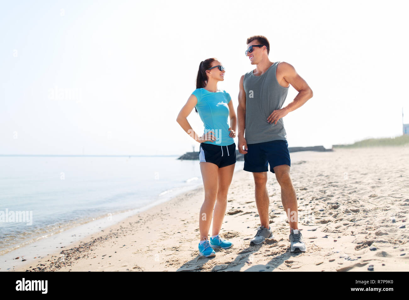 Glückliches Paar in Sportkleidung und Farbtöne auf Strand Stockfoto