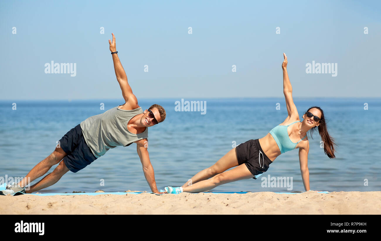 Paar tun seitlicher Ganzkörperstütz Übung auf Sommer Strand Stockfoto