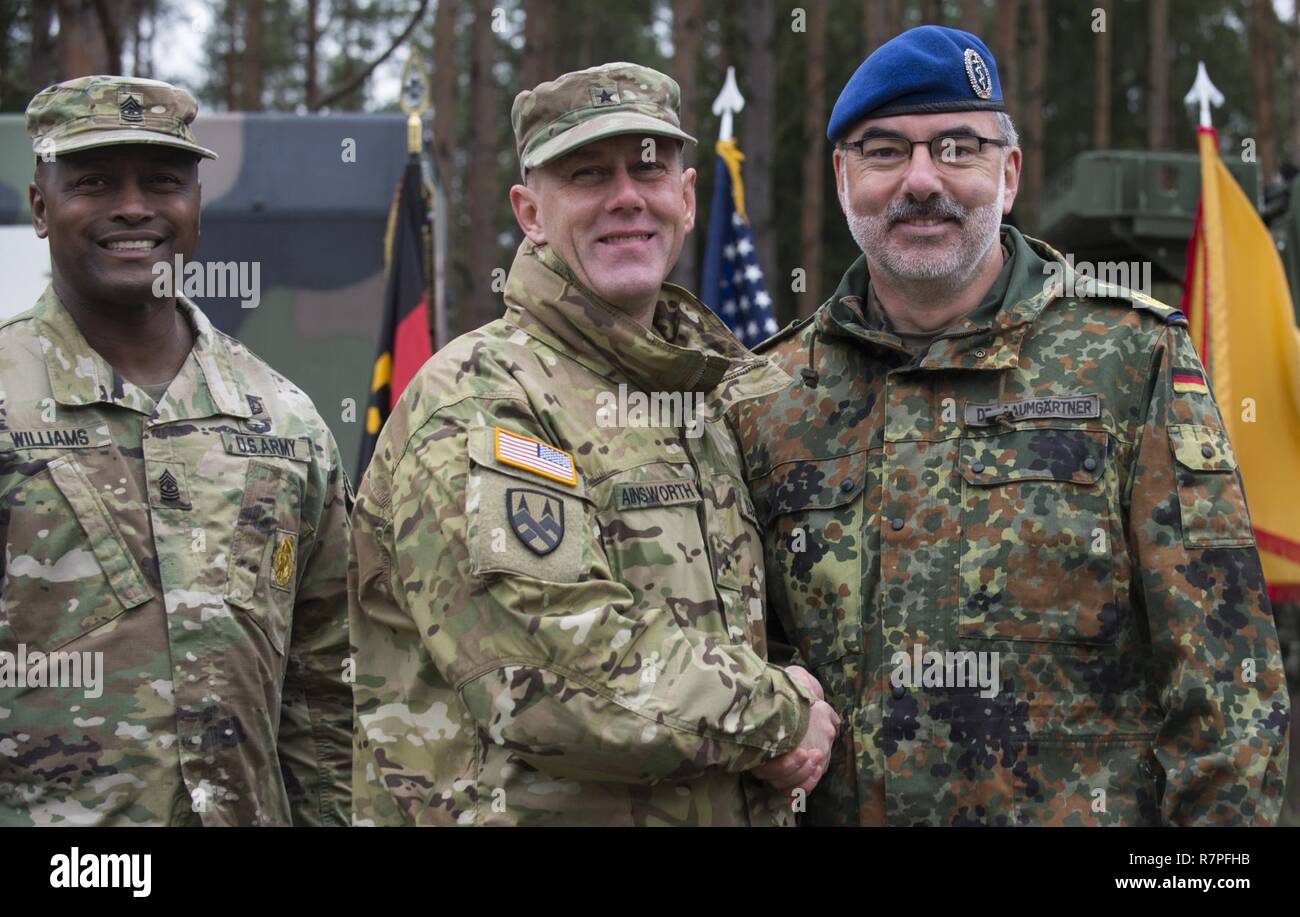 Grafenwöhr, Deutschland - U.S. Army Brigadegeneral Steven Ainsworth (Mitte links), Stellvertretender Kommandierender General des 21 Theater Sustainment Command, schüttelt Hände mit Major General Ulrich Baumgartner (rechts), Kommandierender General der Bundeswehr Operative medizinische Unterstützung Befehl, nach der Unterzeichnung der ersten Einheit Gesellschaftsvertrag der Partnerschaft bei der US-Armee Europa Experten Bereich Medizinische Abzeichen Bewertung in Grafenwöhr, Deutschland am 24. März 2017. Etwa 215 Kandidaten aus der US-Armee und zehn europäischen Partner Nationen nahmen an diesem alle zwei Jahre stattfindenden Bewertung in den Hoffnungen des Erzielens der begehrten Stockfoto