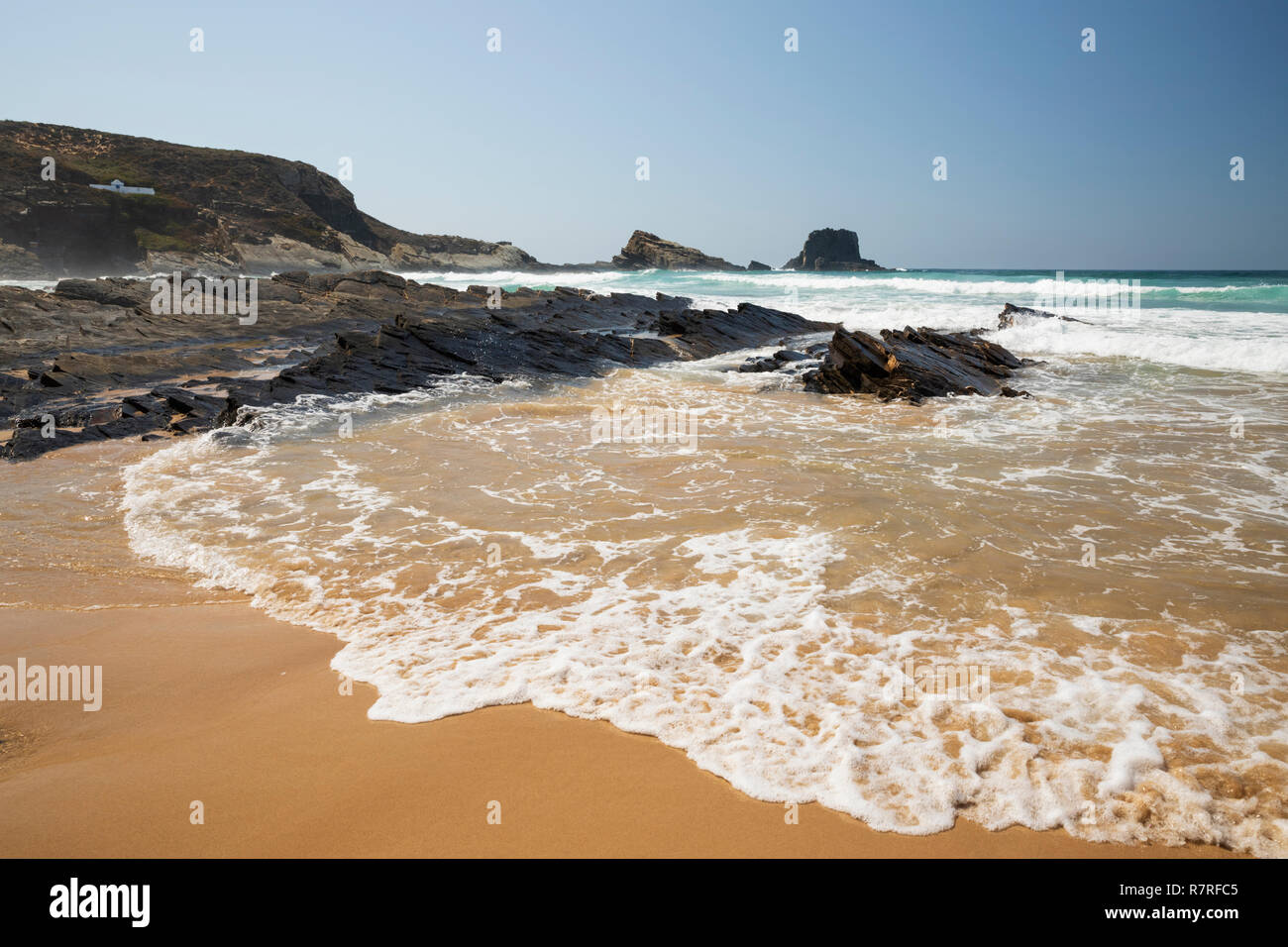Wellen des Atlantiks am Sandstrand in der Morgensonne brechen, Zambujeira do Mar, Alentejo, Portugal, Europa Stockfoto
