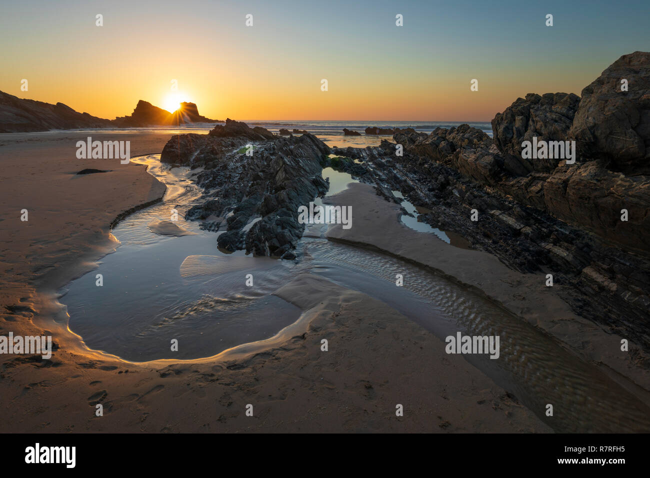 Felsen und Pool am Strand bei Ebbe bei Sonnenuntergang, bei Zambujeira do Mar, Alentejo, Portugal, Europa Stockfoto