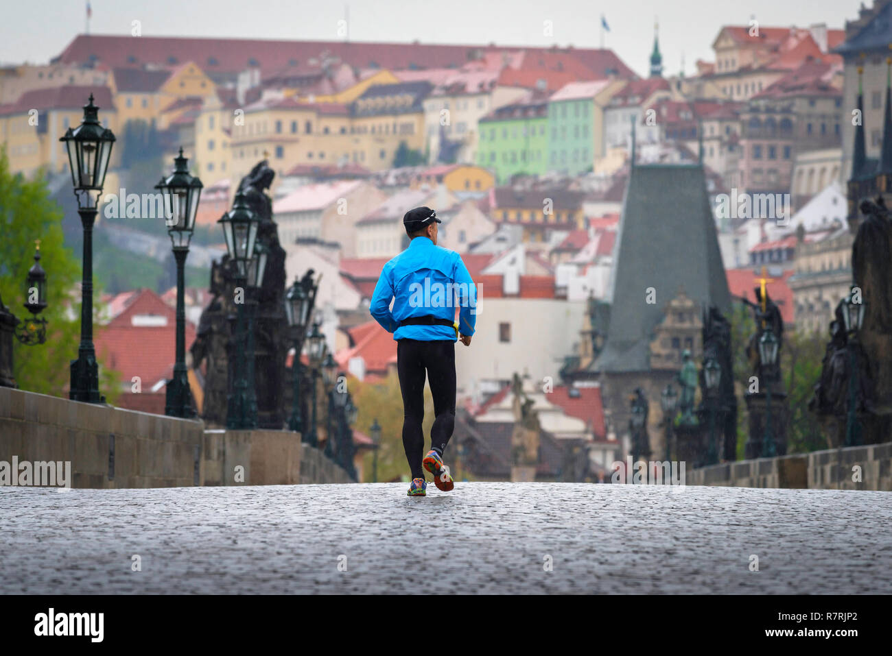 Man joggen Stadt alleine läuft, Ansicht von hinten von einem Mann mittleren Alters, über die Karlsbrücke in Prag an einem bewölkten Tag, Tschechische Republik. Stockfoto