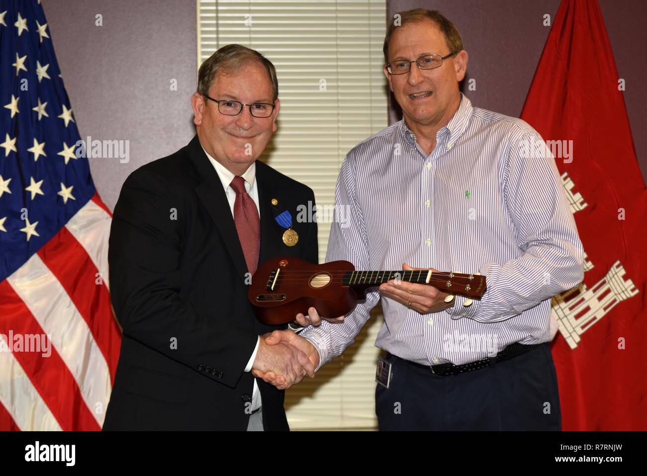 Jimmy Watscheln (Rechts), US-Armee Korps der Ingenieure Nashville Bezirk Engineering und Bau Division Chief, präsentiert eine Ukulele im Namen von Führungskräften zu Mike Wilson, Nashville Bezirk Deputy District Ingenieur für Projektmanagement, seine 42 Jahre des Föderalen Dienstes zu Ehren während einer Ruhestand Feierstunde im bezirk Sitz in Nashville, Tennessee, 31. März 2017. (USACE Stockfoto