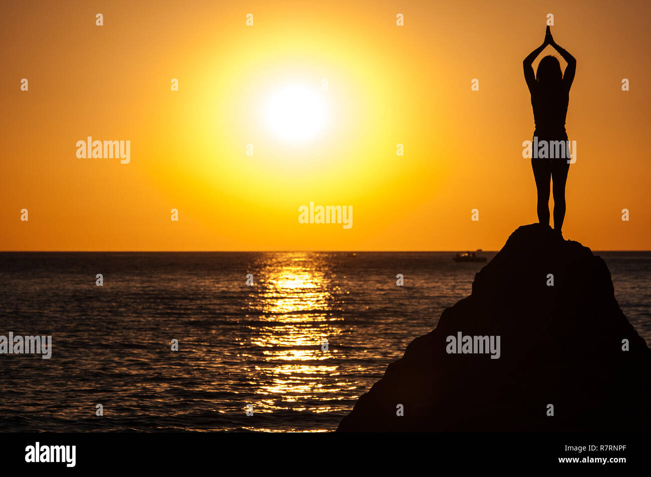 Argelès-sur-Mer (Frankreich). Jemand Yoga auf den Felsen vor der Racou Strand bei Sonnenaufgang. Schöne junge Frau mit langen b Stockfoto