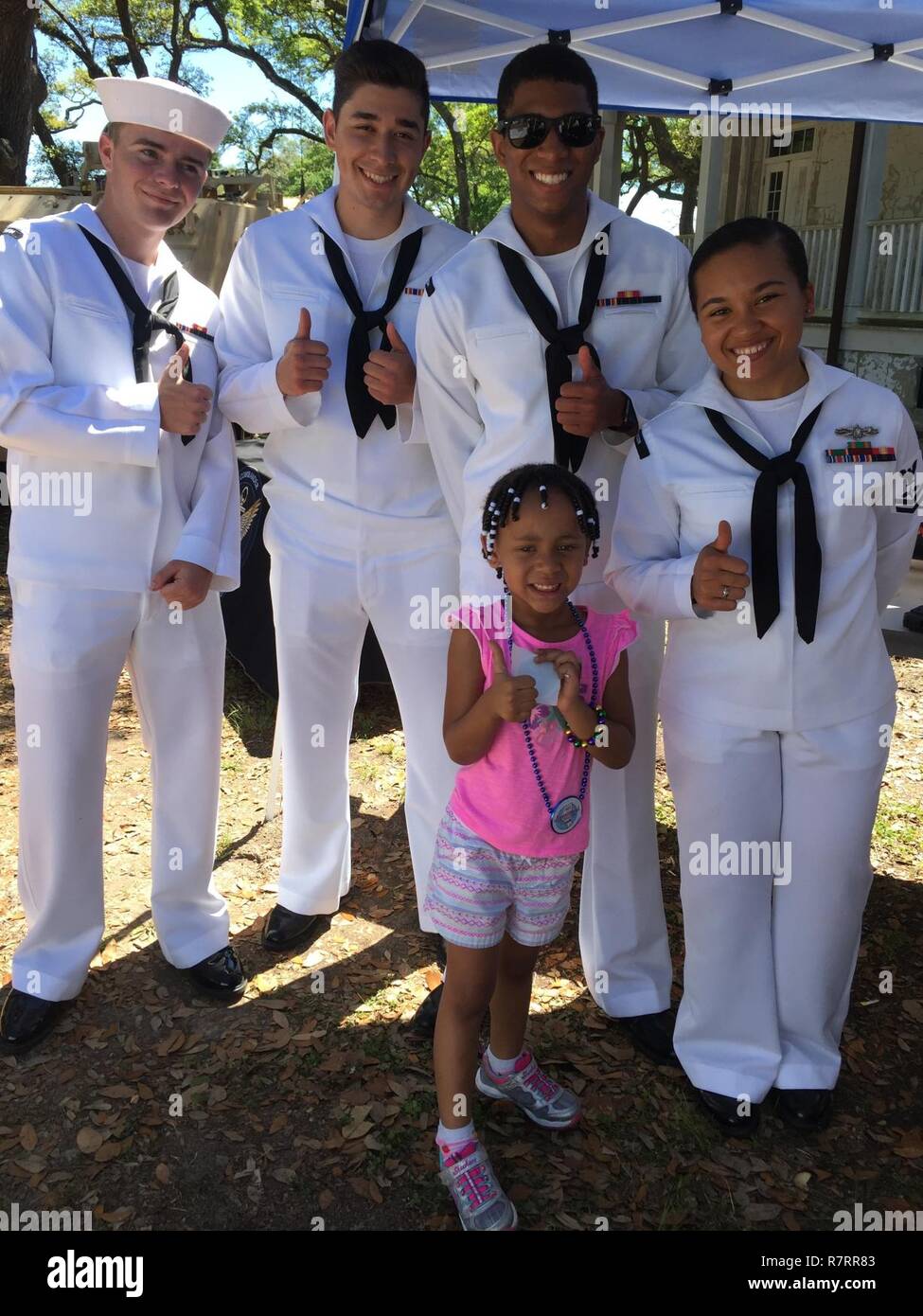 Seeleute aus dem Naval Ozeanographie Minenkrieg Center stellen mit einem kleinen Besucher am Mississippi Bicentennial während Marine Woche Mississippi Gulf Coast am 1. April. Im Bild von links nach rechts sind Flieger Brandon Vanbuytene, Flieger Alex Torres, Flieger McKinley Wyche und Petty Officer Alecx Morgan. Stockfoto