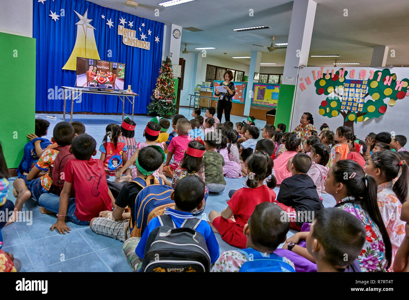 Thailands Schule Weihnachten. Der Lehrer erklärt Weihnachten und zeigt einen Film in einem Klassenzimmer mit kleinen Kindern Stockfoto