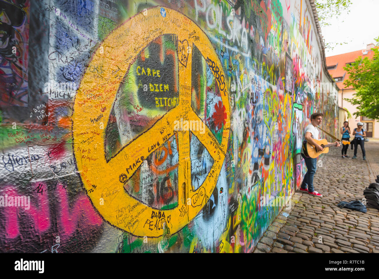 Prag John Lennon Mauer, mit Blick auf ein strassenmusikant spielt eine Gitarre neben den John Lennon Mauer in der Mala Strana Viertel von Prag, tschechische Republik. Stockfoto