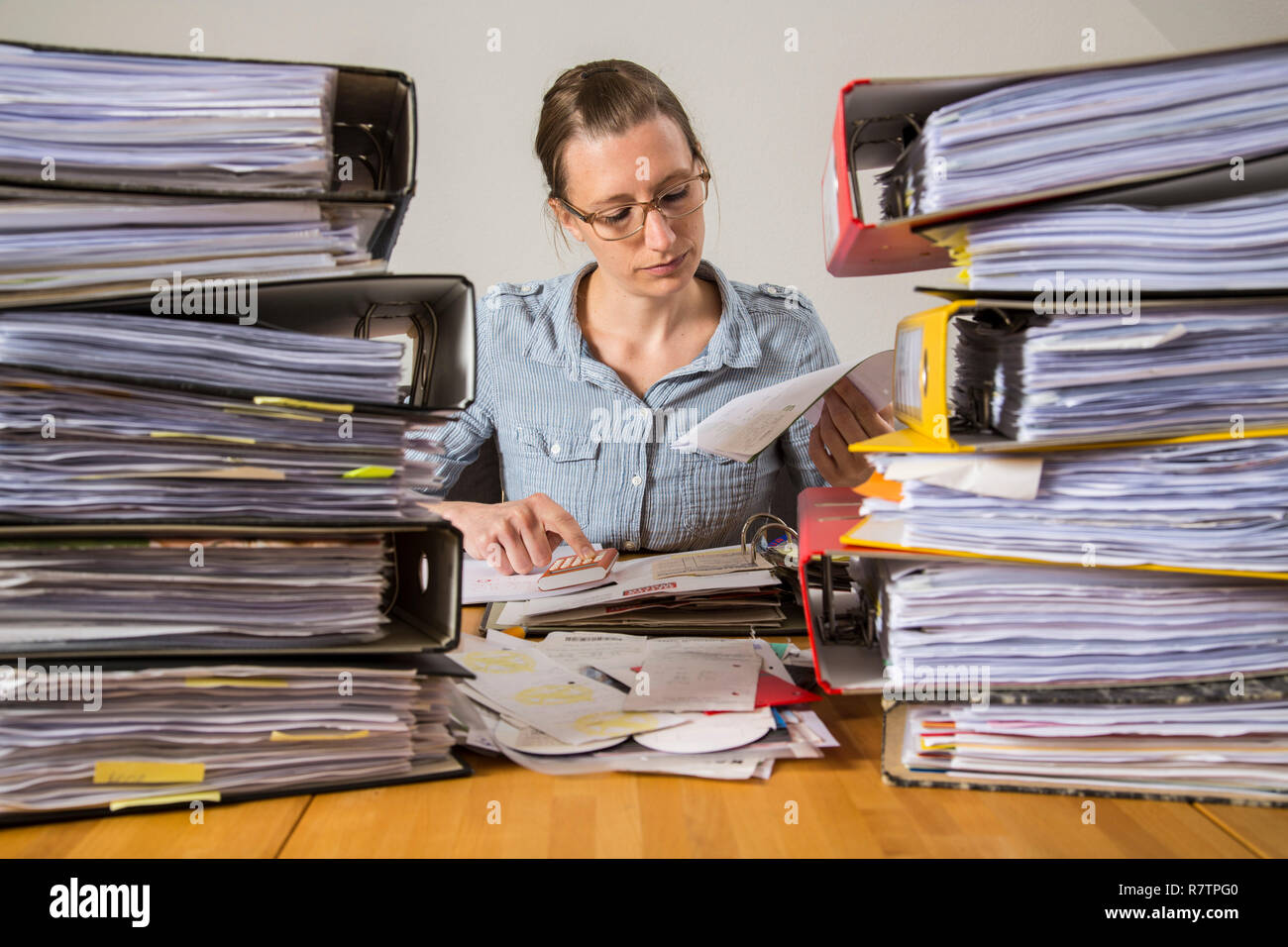 Frau am Schreibtisch zwischen den Stapeln mit Dateien arbeiten Stockfoto