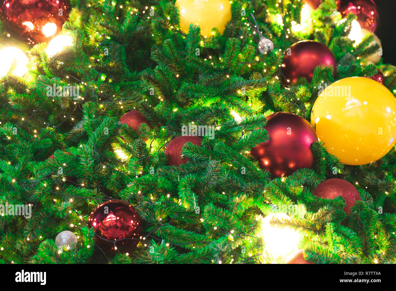 Schließt Weihnachtsbaum durch Licht und rote Kugeln dekoriert Stockfoto