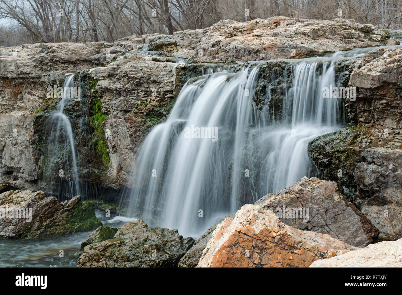 Wasserfall unter Felsbrocken auf einen warmen Winter Tag bildet eine malerische Aussicht Stockfoto