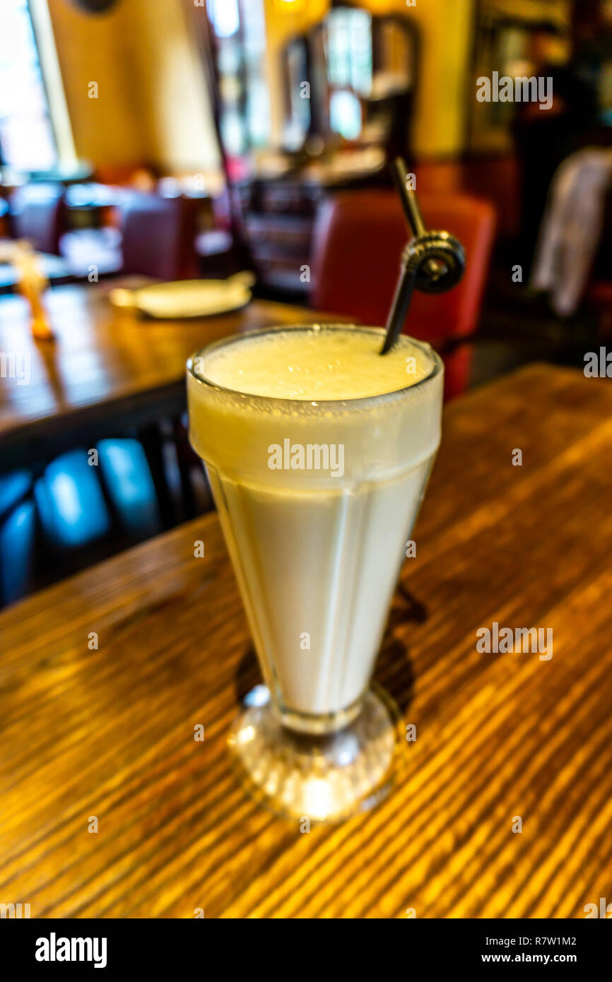 Gemeinsame Mango Lassi in einem langen Glas mit einem geschweiften Schwarz Stroh Stockfoto