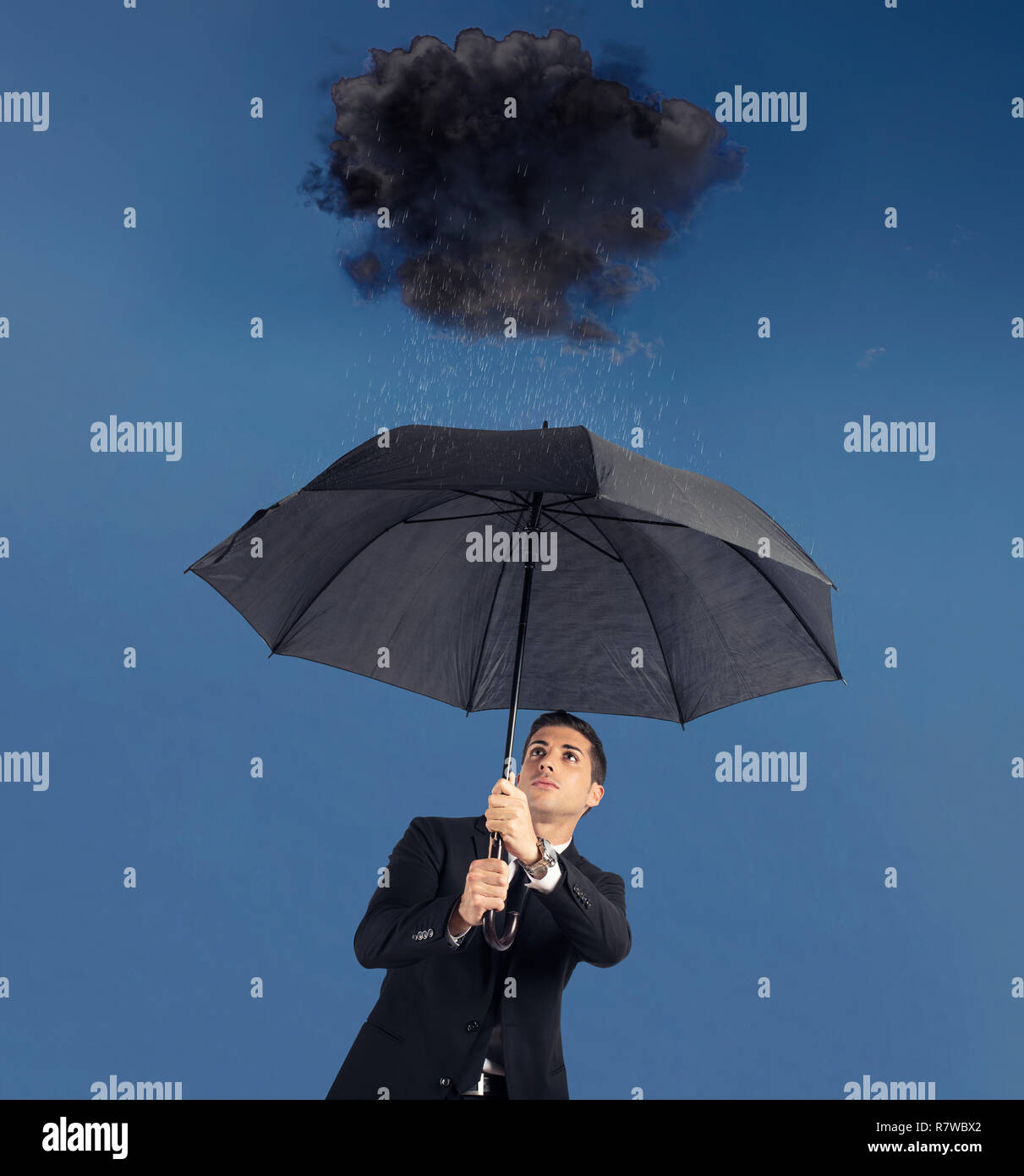 Geschäftsmann mit Regenschirm und eine schwarze Wolke mit Regen. Konzept der Krise und finanzielle Schwierigkeiten Stockfoto