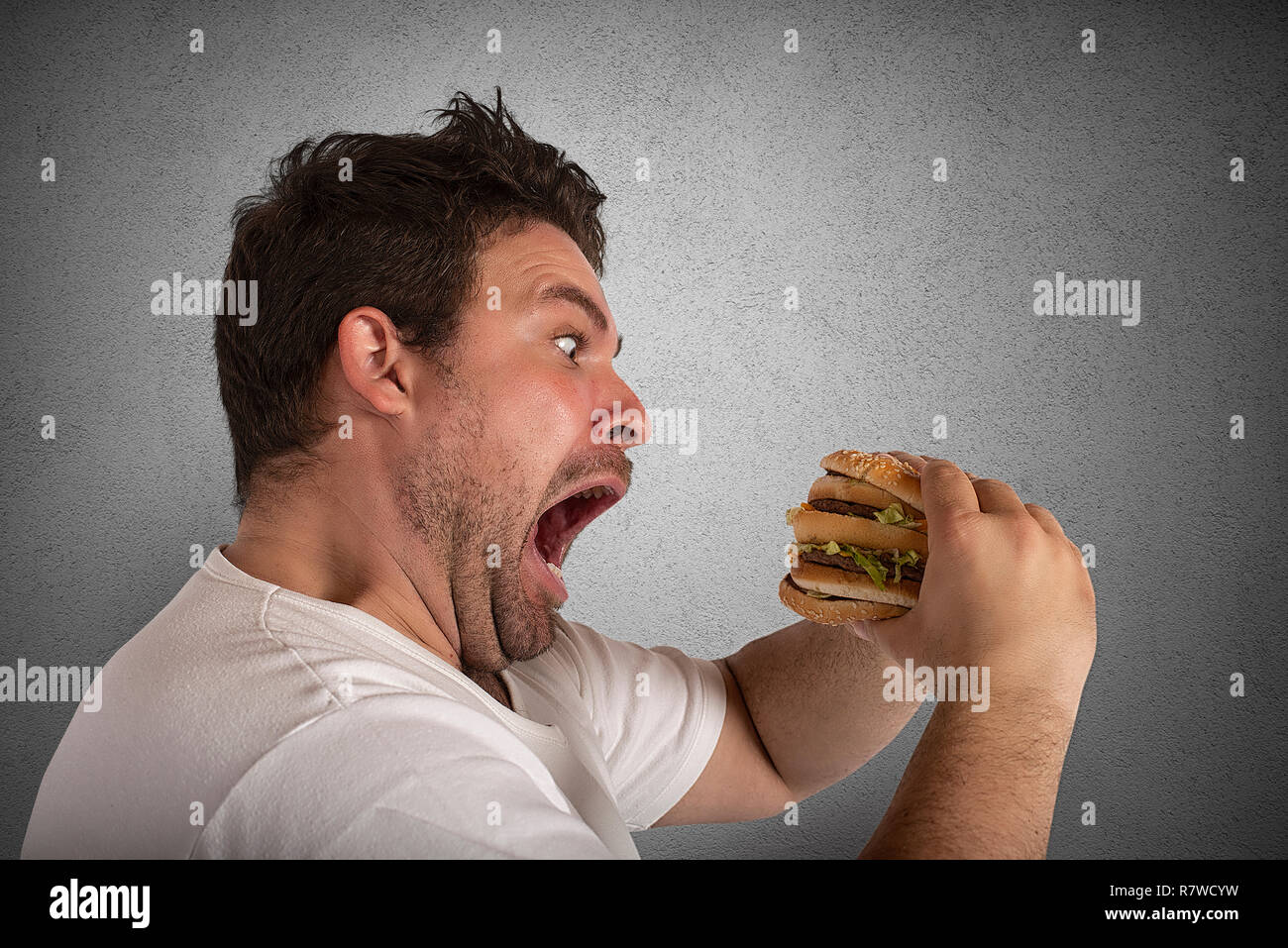 Unersättlich und hungrigen Mann essen ein Sandwich Stockfoto