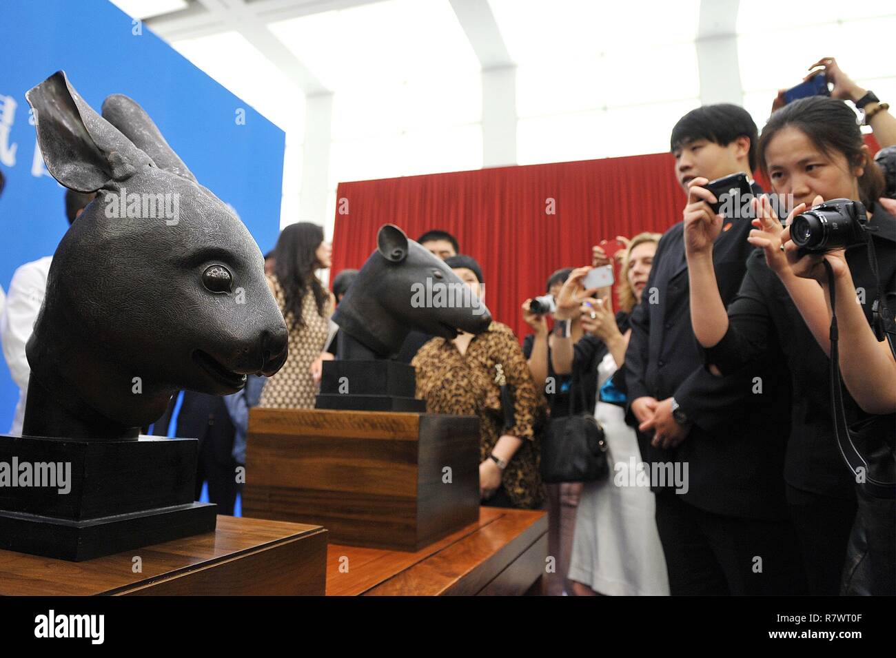 (181212) - Peking, Dez. 12, 2018 (Xinhua) - Datei Foto am Juni 28, 2013 Leute zeigt, die Bilder von zwei bronzenen Tierkopf Skulpturen von westlichen Eindringlinge eineinhalb Jahrhunderten während einer Übergabe der Regierungschefs in Peking, der Hauptstadt von China geplündert. Die Staats- und Regierungschefs eine Ratte und ein Kaninchen, Teile einer Fontänenuhr, die zuvor bei der alten Sommerpalast Yuanmingyuan', oder 'in der chinesischen standen, wurden am 26. April, gestiftet 2013 durch den Pinault Familie. Eine Chinesische bronze Schiff geplündert von Yuanmingyuan, oder der alte Sommerpalast, hat kürzlich nach China zurück und betrat das Sammeln Stockfoto