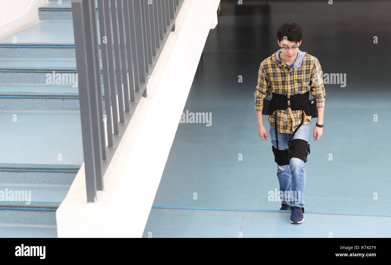 (181212) - Shenzhen, Dez. 12, 2018 (Xinhua) - Forscher Fang Kai Tests eine flexible Exoskelett Roboter in Shenzhen Institut für Advanced Technology (SIAT) der Chinesischen Akademie der Wissenschaften in Shenzhen in der Provinz Guangdong im Süden Chinas, Dez. 11, 2018. Exoskelett Roboter, von der Shenzhen Institut für Advanced Technology (SIAT) der Chinesischen Akademie der Wissenschaften produziert, ist für die Rehabilitation Ausbildung im Krankenhaus und der persönlichen Betreuung zu Hause verwendet. Der Roboter besteht aus kompletten Antriebs- und Steuerungssystems, ein paar smart Krücken, multi-sensor System und verstellbare Struktur der aktiven Verbindungen. Gelähmt Stockfoto