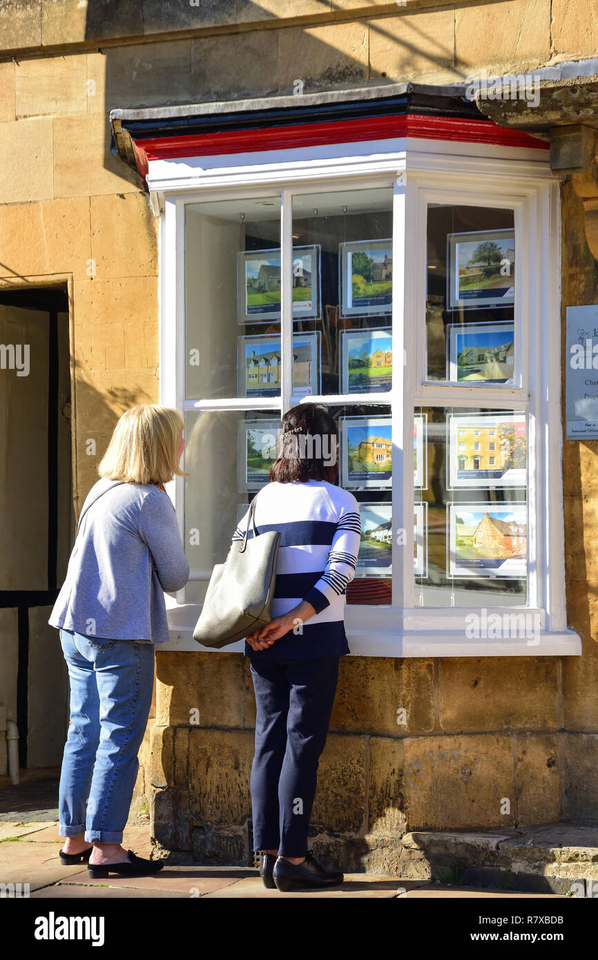 Die Frauen, die im Fenster "estate agent, High Street, Chipping Campden, Gloucestershire, England, Vereinigtes Königreich Stockfoto