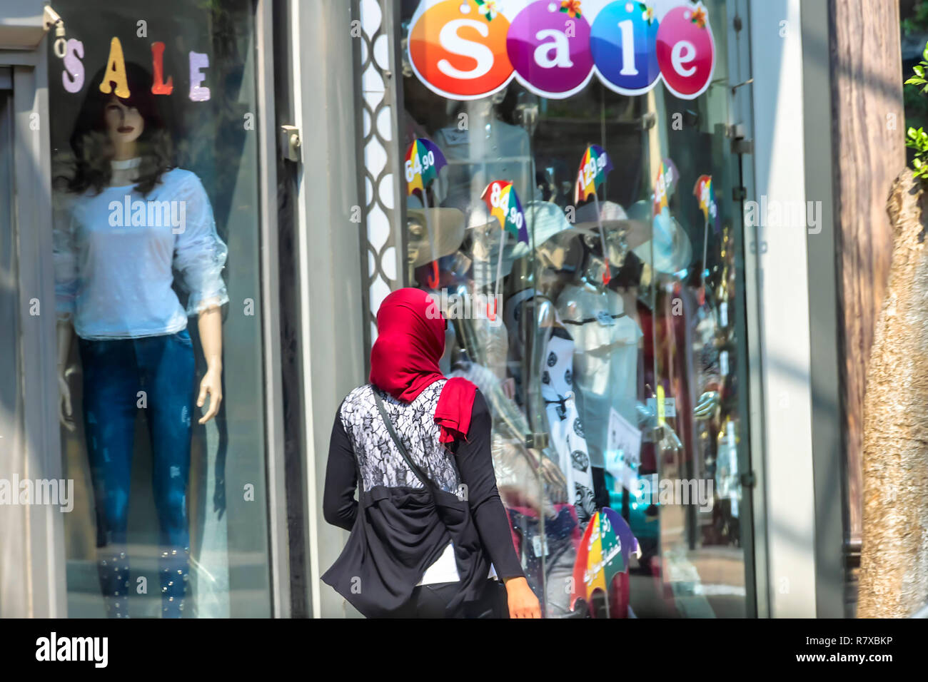 Kairo, Ägypten, 16. September 2018: die arabische Frau mit roten Kopftuch vor eine verwestlichte Shop, in Kairo, Ägypten. Stockfoto