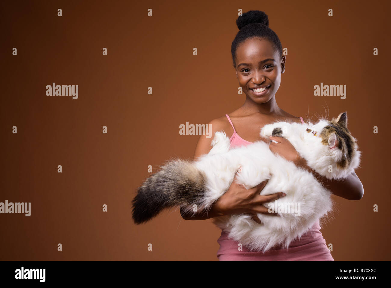 Junge schöne afrikanische Zulu Frau mit Katze während lächelnd Stockfoto